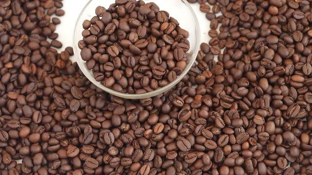 Micro shot of dropping glass bowl filled with coffee beans over heap of coffee beans