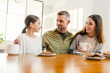 Fototapeta premium Happy masculine military man hugging his family while having breakfast