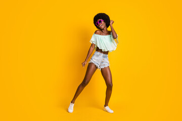 Fototapeta na wymiar Full length body size photo of black skinned girl dancing in wearing star shaped sunglass shorts top isolated on vivid yellow color background