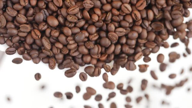 Close view of dropping coffee beans over white background