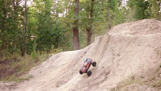 RC car does somersault. Radio controlled toy car rolling over the sandy hill.