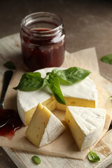 Concept of tasty eating with camembert and jam on cutting board