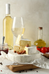 Concept of tasty eating with camembert, hazelnut and wine on white table