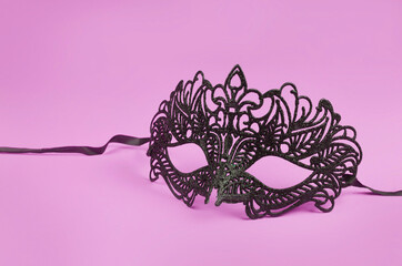 Venetian delicate black mask on pink background.