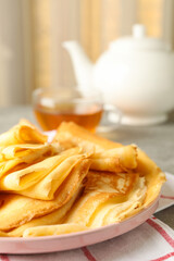 Tea, and plate of thin pancakes on gray table