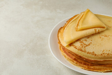 Plate with thin pancakes on white textured background