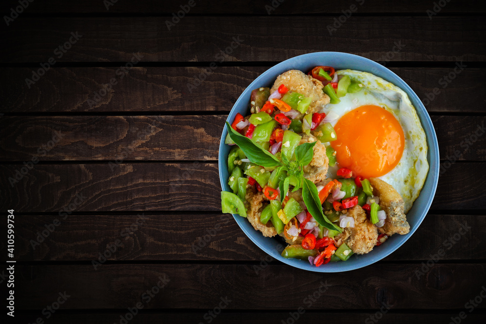 Wall mural Rice in a bowl filled with beef eye eggs and chopped fried fish smothered in very hot chili sauce.