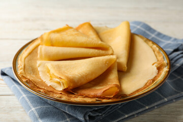 Kitchen towel with plate of thin pancakes on wooden background