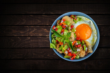 Rice in a bowl filled with beef eye eggs and chopped fried fish smothered in very hot chili sauce.