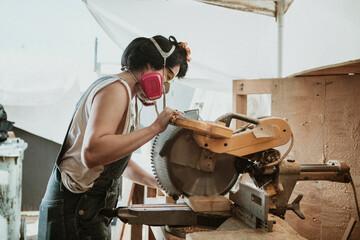 Female carpenter using a compound miter saw