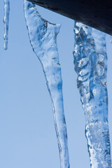 Closeup icicles background. Icicles hanging down from a roof. Cold weather, winter season