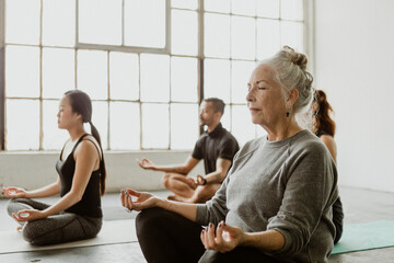 Diverse people meditating in a yoga class - 410601320