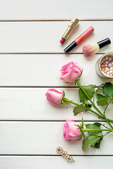 Top view arrangement with make-up, roses, hairpin and copy-space on white wooden background