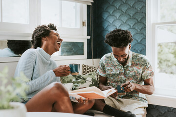 Happy black couple reading a book at home - Powered by Adobe