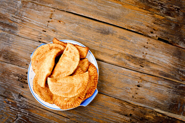 Homemade chebureks filled with minced meat and onions, traditional Caucasian and Russian cuisine. Close-up of group of fresh fried meat pastry pie called cheburek on wooden table.