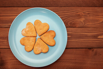 Heart cookies for Valentine's Day are laid out on a wooden background.