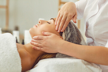 Close up shot of a professional masseuse doing a facial and head massage for her female client.