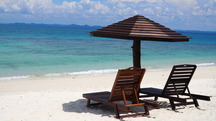 Beach chairs with umbrella and beautiful white sand beach. Panorama of tropical beach with white sand and turquoise water. Travel summer holiday background concept