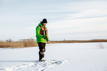 young man on a winter fishing trip on a snowy lake fishes on a fishing rod