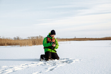 Fototapeta na wymiar young man on a winter fishing trip on a snowy lake fishes on a fishing rod