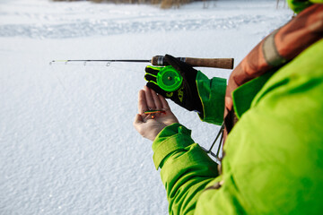 young man on a winter fishing trip on a snowy lake fishes on a fishing rod