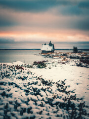 Minimalist snowy winter landscape with authentic wooden house at dusk on the beach in a Russian village Rabocheostrovsk.