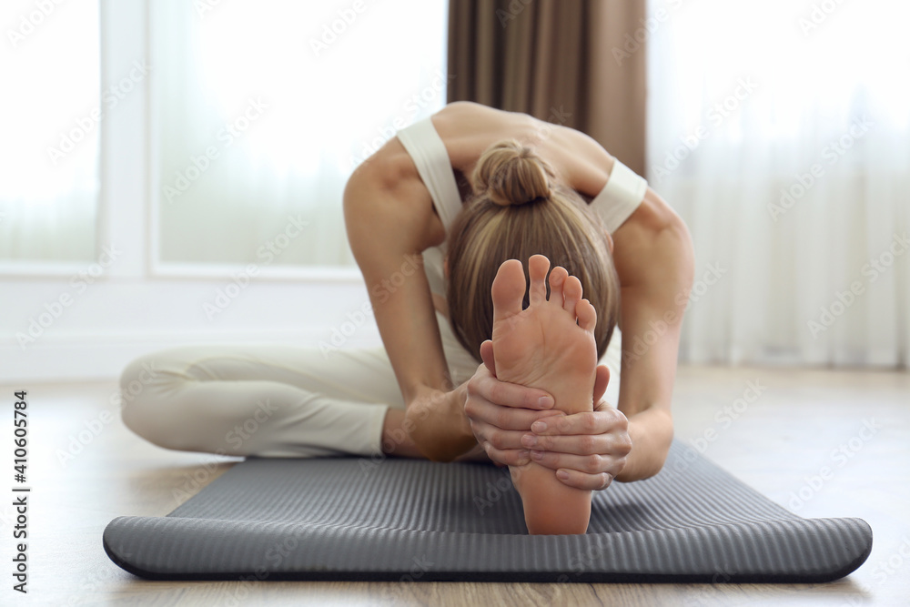 Canvas Prints Young woman practicing head to knee asana in yoga studio, focus on foot. Janu Sirsasana pose