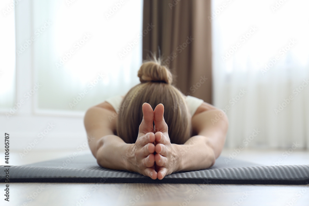 Wall mural Young woman practicing restorative asana pose in yoga studio, focus on hands