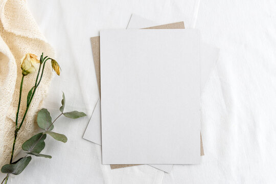 Fashionable stock stationery background - a white card for writing and twigs of dry plants on a white table. Wedding feminine background.