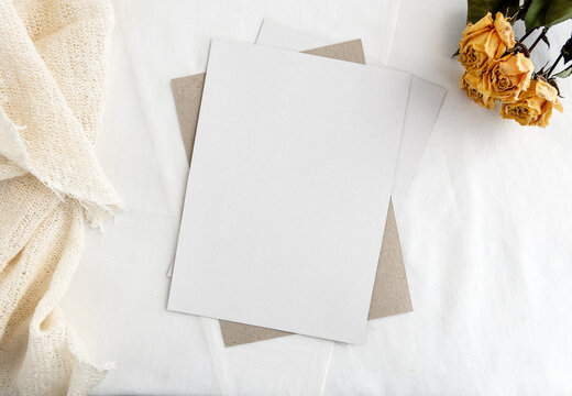 Fashionable stock stationery background - white card for lettering and dry yellow roses on a white table. Wedding feminine background. Blank for an invitation card.