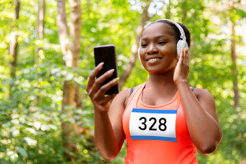 fitness, sport and technology concept - happy smiling young african american woman or marathon...