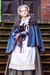 Naklejka premium Nineteenth-century woman, elegantly dressed, walks through the courtyard of a castle.