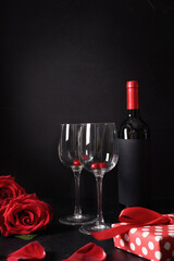 Valentine's day romantic dating with red roses, wine and chocolate sweets on black. Vertical greeting card.