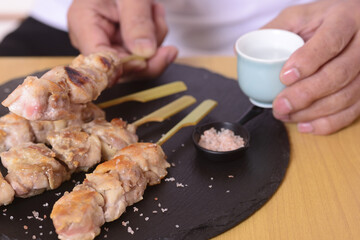 日本酒を呑むシニアの手と焼き鳥