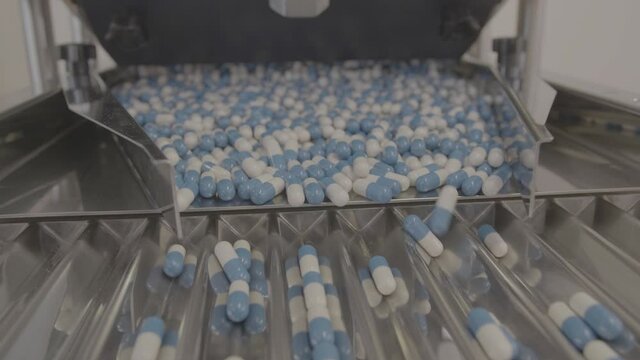Drug Production. Blue and white pills. Pharmaceutical machinery for medicine production Pills shot in V-Log