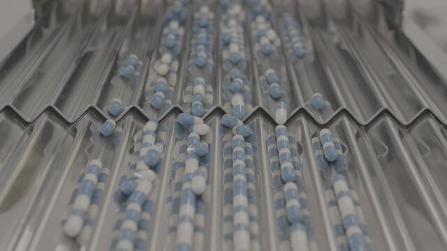 Drug Production. Blue and white pills. Pharmaceutical machinery for medicine production Pills shot in V-Log
