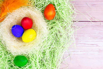 Fototapeta na wymiar Top view flat lay colorful painted Easter eggs decorations in the nest with copy space on light wooden background.