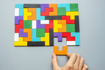 hand connecting geometric shape block with colorful wood puzzle pieces. logical thinking, business...