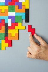 hand connecting geometric shape block with colorful wood puzzle pieces. logical thinking, business...