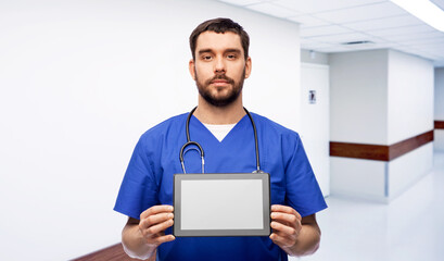 Obraz na płótnie Canvas medicine, healthcare and technology concept - doctor or male nurse in blue uniform with stethoscope showing tablet pc computer over hospital corridor on background