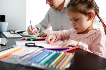 daughter draws with father sitting at the table