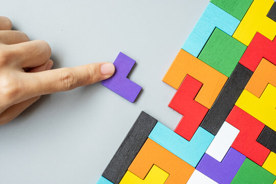 hand connecting geometric shape block with colorful wood puzzle pieces. logical thinking, business logic, Conundrum, decision, solutions, rational, mission, success, goals and strategy concepts