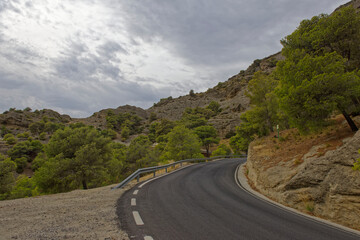 A deserted narrow winding road passing through the Mountain Scenery of central Andalusia on an overcast evening in October.