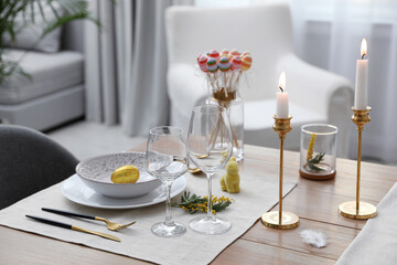 Beautiful Easter table setting with burning candles and floral decor indoors