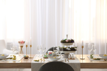 Beautiful Easter table setting with burning candles and floral decor indoors