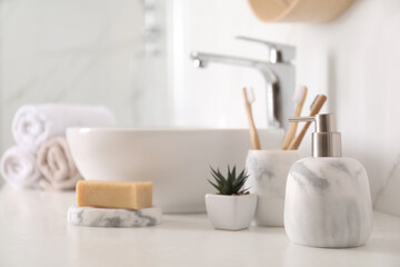 Holder with toothbrushes, plant and different toiletries near vessel sink in bathroom