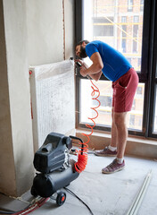 Plumber filling pipes with air to inspect for leaks in new installation, using air compressor while...