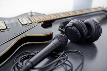 leisure, music and musical instruments concept - close up of bass guitar, microphone and headphones on black table