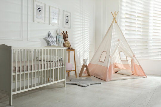 Comfortable crib and play tent in baby room. Interior design