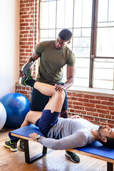 Fit coach stretching a client